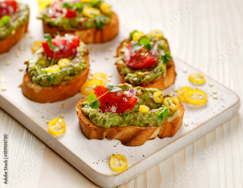 Sandwiches with guacamole, cherry tomatoes, onions, chili peppers and fresh coriander. A delicious and healthy vegetarian appetizer