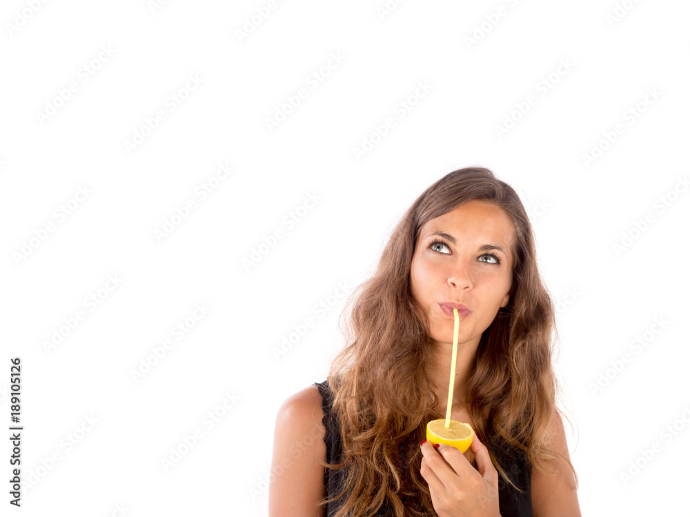 Beautiful girl drinking some natural juice from a real lemon; health and lifestyle concepts, customizable background with copy space Beautiful girl drinking some natural juice from a real lemon; health and lifestyle concepts, customizable background with copy space
