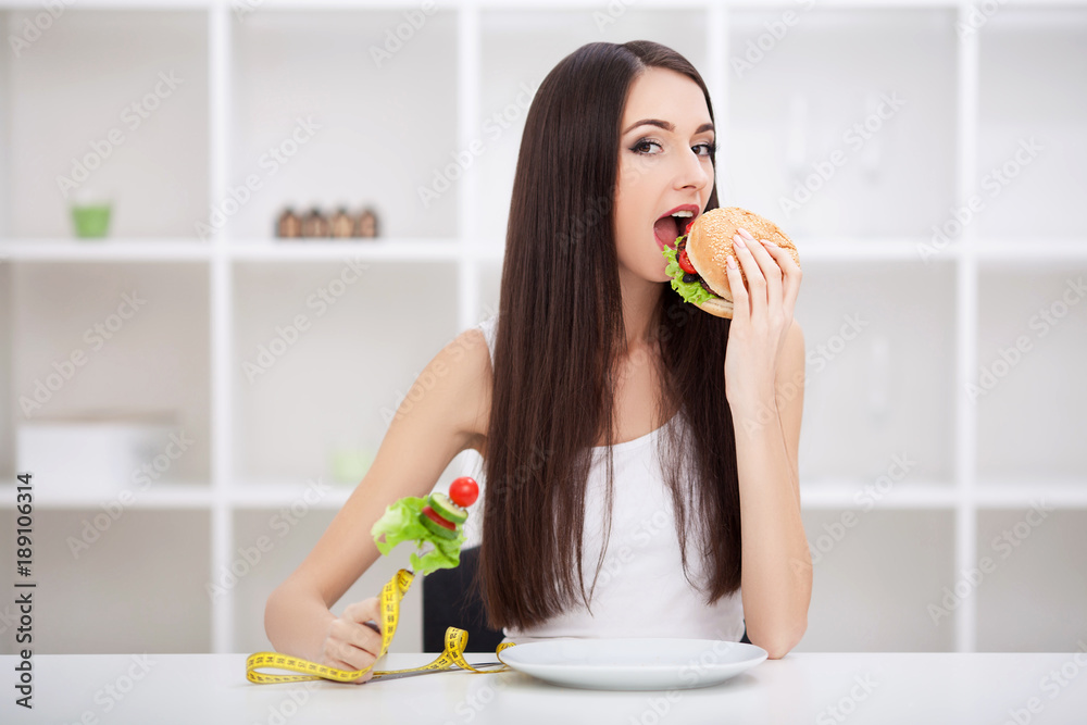Attractive young woman makes a choice between healthy and unheal Attractive young woman makes a choice between healthy and unheal