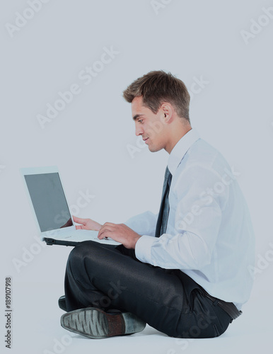 Isolated seated young businessman using a laptop
