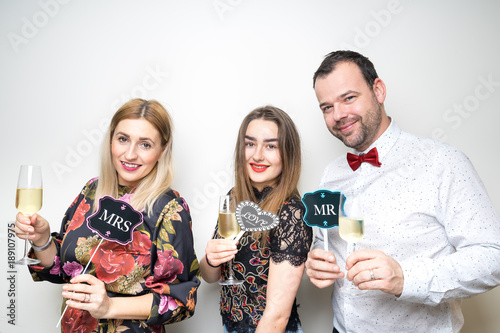 Obraz na płótnie three people girls man posing party props photo booth white plain background studio hat w salonie