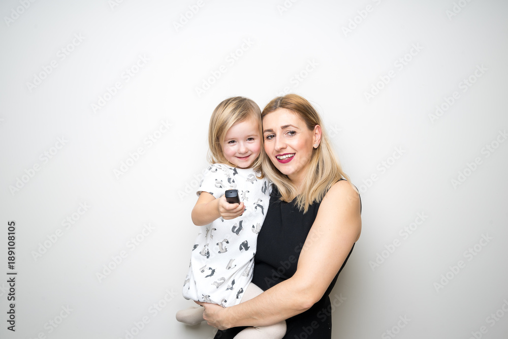 young mom and daugter baby girl posing photo booth remote control camera plain background studio
