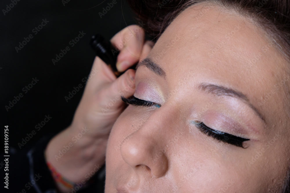 Makeup artist applies eye shadow. Beautiful woman face. Perfect makeup in pinup or pin up style