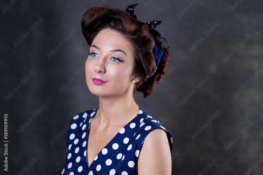 Portrait of beautiful pinup model in blue polka dot dress and bow Portrait of beautiful pinup model in blue polka dot dress and bow