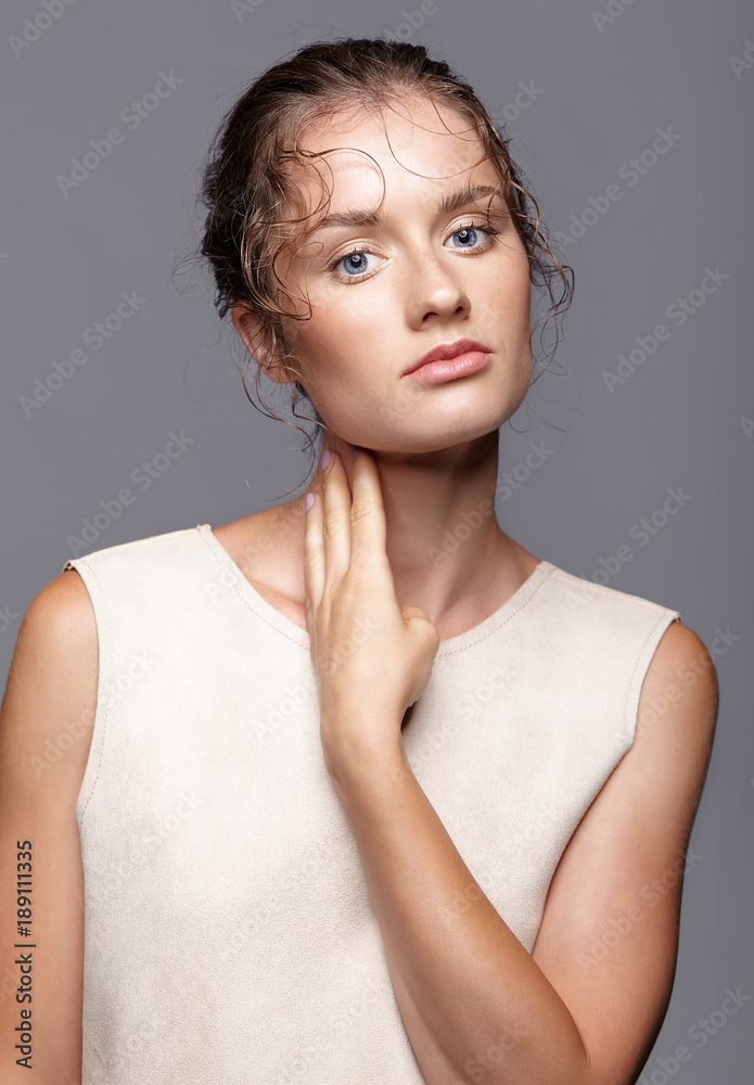 Beauty portrait of young woman. Brunette girl with bright blue eyes and day female makeup on gray background Beauty portrait of young woman. Brunette girl with bright blue eyes and day female makeup on gray background