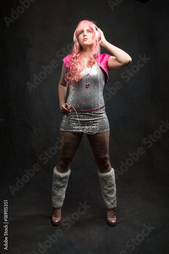 Dancing girl with headphones in sparkling dress, dark background