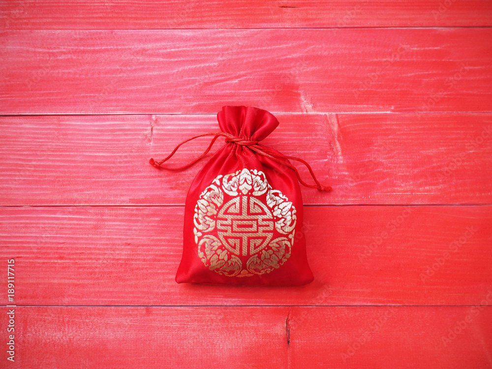 Red silky money bag with string on wood background