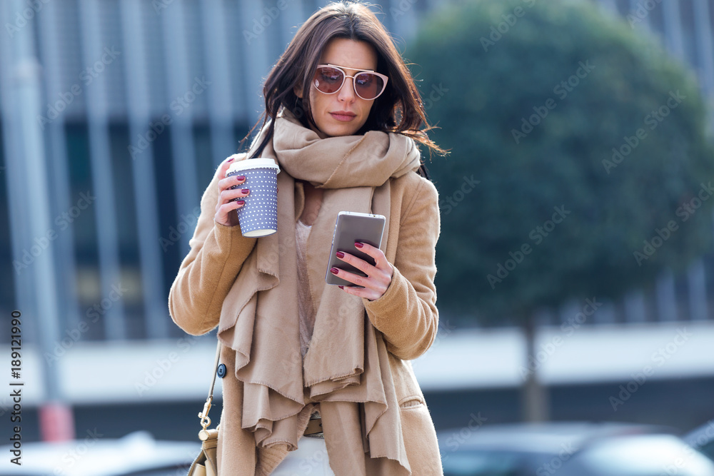 Fototapeta premium Beautiful young woman using her mobile phone in the street.