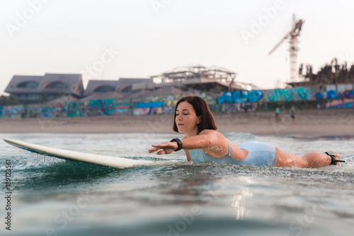Photography Young woman in bright bikini surfing on a board in ocean