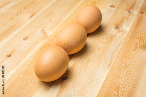 Three chicken eggs lie on a wooden board