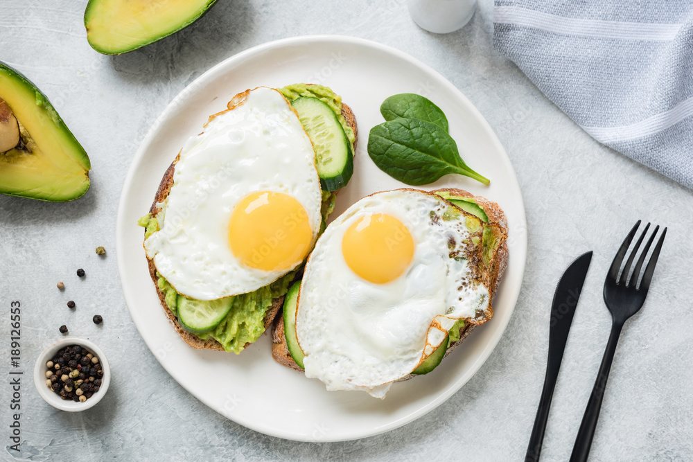 Egg and avocado breakfast toast on white plate. Table top view. Healthy eating dieting concept Egg and avocado breakfast toast on white plate. Table top view. Healthy eating dieting concept