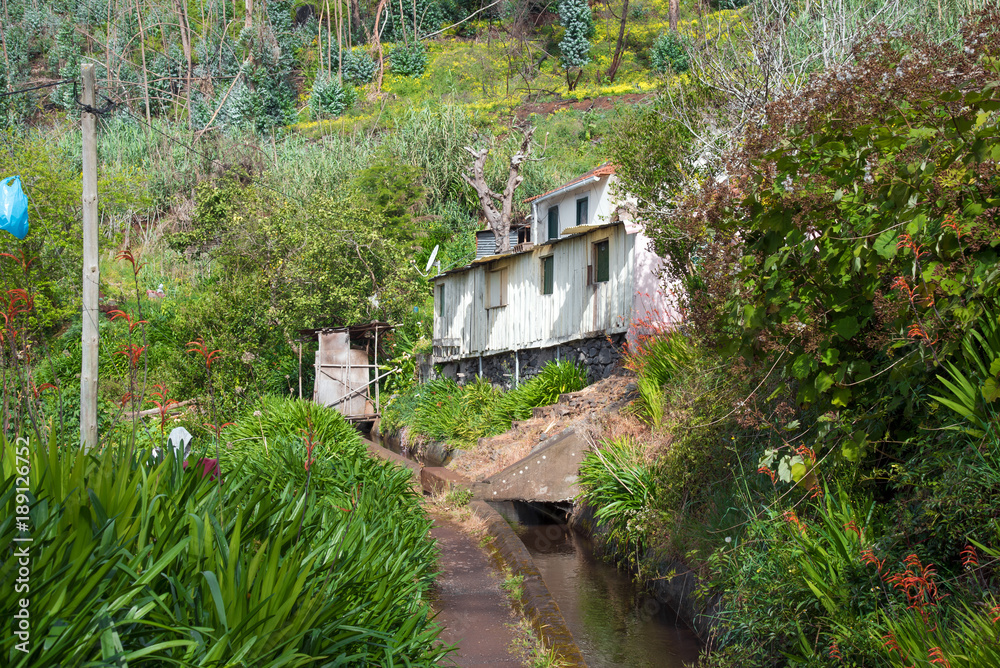 Levada trail with a wayside house. Leavdas are irrigation channels specific to the island of Madeira often with a public footpath on the side. Levada trail with a wayside house. Leavdas are irrigation channels specific to the island of Madeira often with a public footpath on the side.