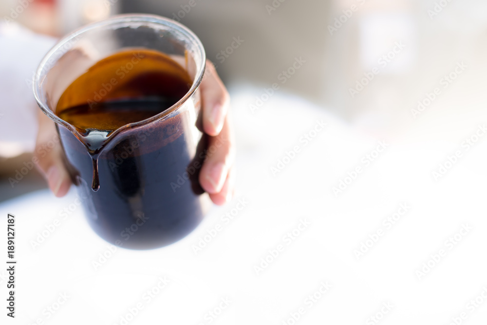 Molasses sugarcane on beaker. Droping molasses with hands. Molasses is the final product from