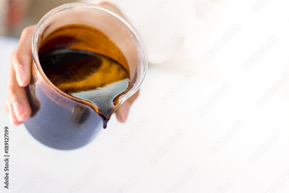 Molasses sugarcane on beaker. Droping molasses with hands. Molasses is the final product from