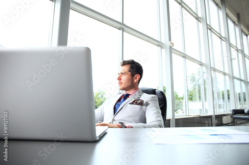 Portrait of young man sitting at his desk in the office