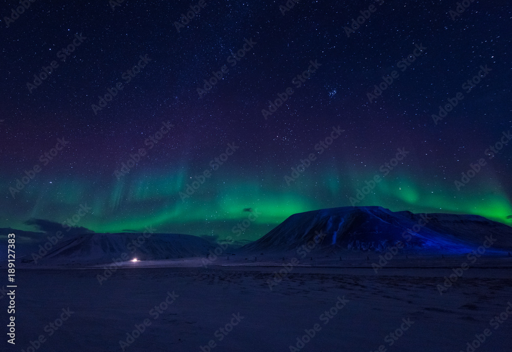 The polar arctic Northern lights aurora borealis sky star in Norway Svalbard in Longyearbyen city town mountains