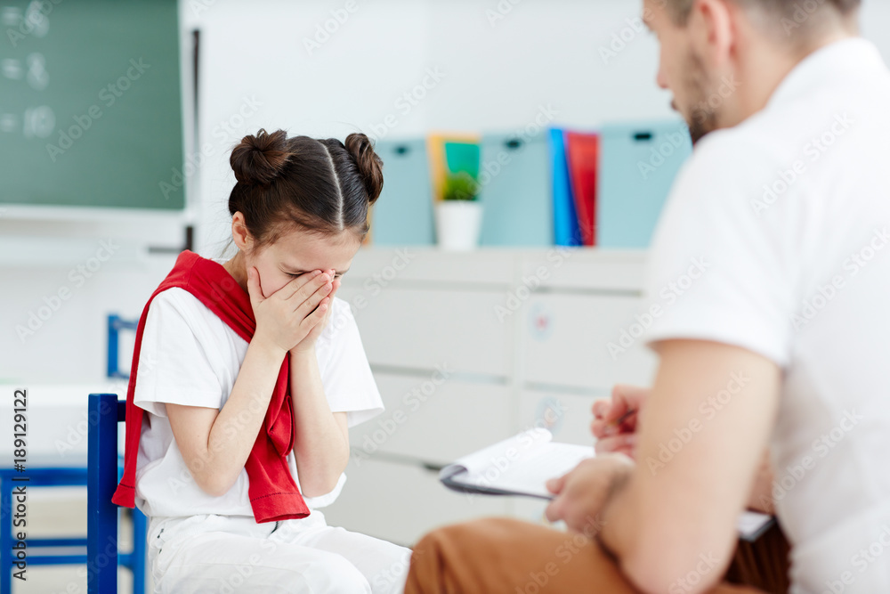 Little schoolgirl crying in front of her teacher because she does not know the answer Little schoolgirl crying in front of her teacher because she does not know the answer