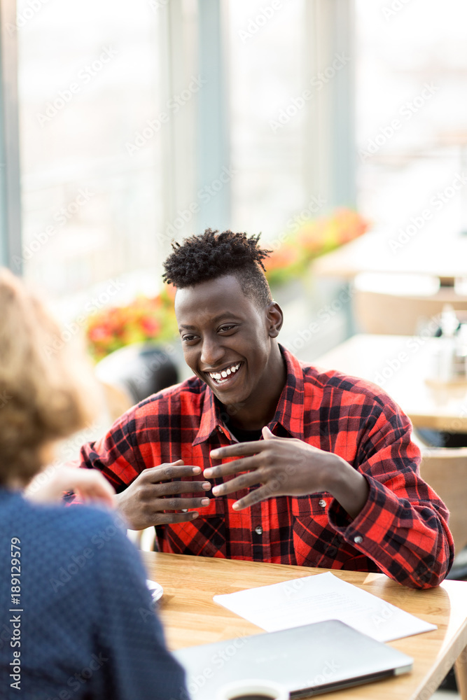 Obraz premium Happy African-american man in casualwear discussing working plans with colleague
