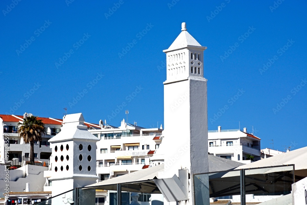 Traditional Portuguese chimneys with town apartments to the rear, Albufeira, Algarve, Portugal.