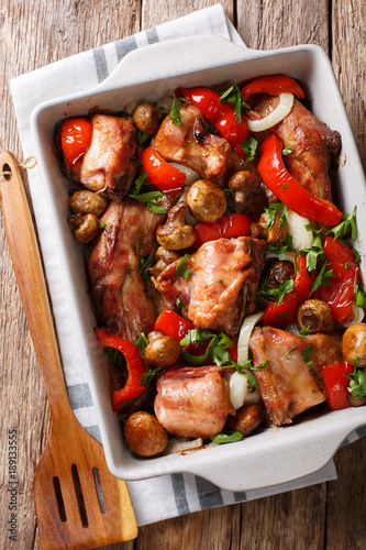 Delicious healthy rabbit baked with mushrooms and vegetables close-up in a baking dish. Vertical top view