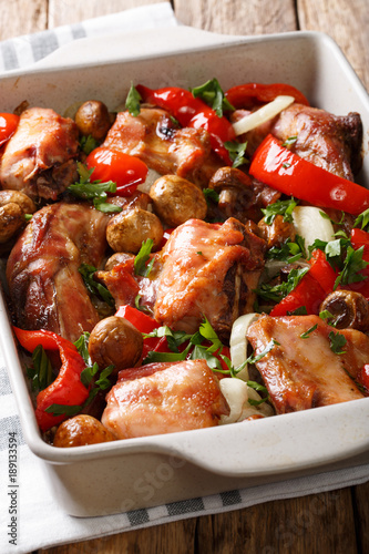 Organic diet food: rabbit baked with mushrooms, pepper and onions close-up in a baking dish on a table. vertical