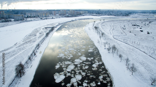 Ice swims in the river. Winter landscape photographed from above near the city. Top view. Nature and abstract background