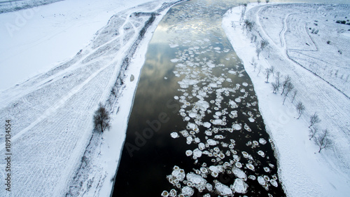 Ice swims in the river. Winter landscape photographed from above. Top view. Nature and abstract background