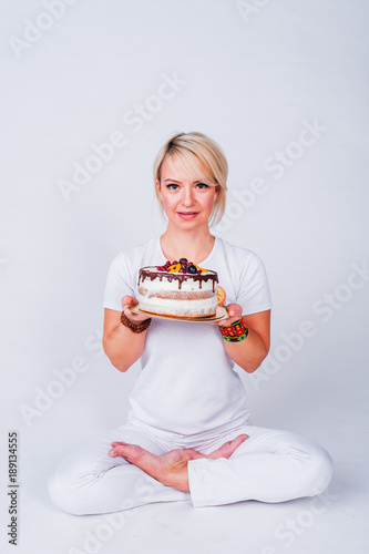 Foto Yogi girl in a white suit holding a cake and wants to bite him