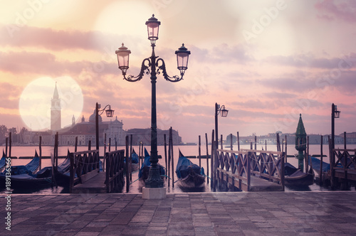 Venice classic sunrise view with gondolas on the waves and bokeh lights