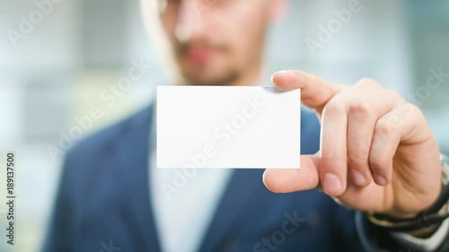 A handsome businessman showing a blank piece of paper. Close-up shot. Soft focus.
