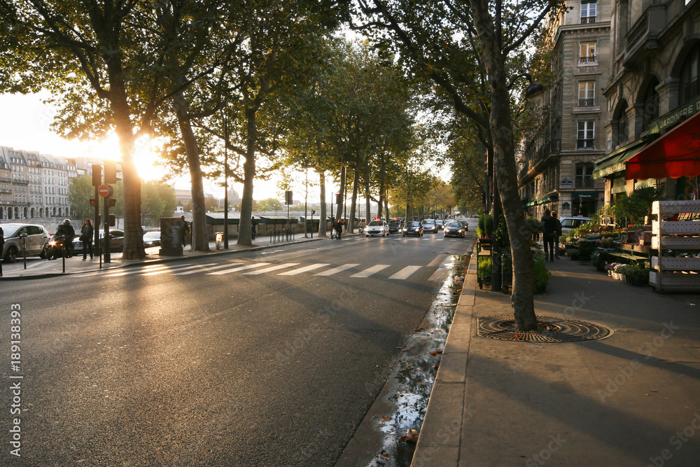 a typical Parisian street, Autumn quay of the Seine, sunset, walkway, fruit shop, the car on the road, motorcyclist
