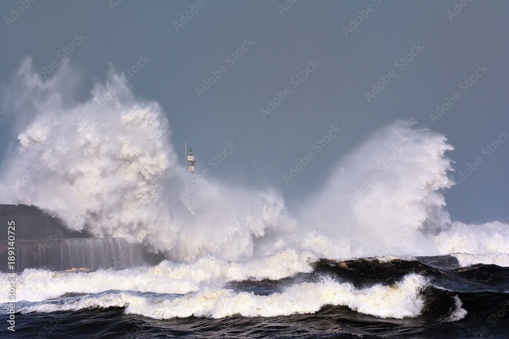 Obraz premium Stormy wave over lighthouse of San Esteban de Pravia.