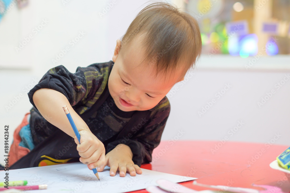 Cute little Asian 18 months / 1 year old toddler baby boy child drawing with pencil at art class, kid write with nursery teacher in a kindergarten,Creative play for toddlers concept - Selective focus Cute little Asian 18 months / 1 year old toddler baby boy child drawing with pencil at art class, kid write with nursery teacher in a kindergarten,Creative play for toddlers concept - Selective focus