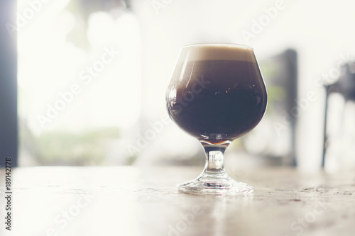 frothy sparkling nitro cold brew ready to be served at coffee shop bar environment background. coffee machine wooden table vintage