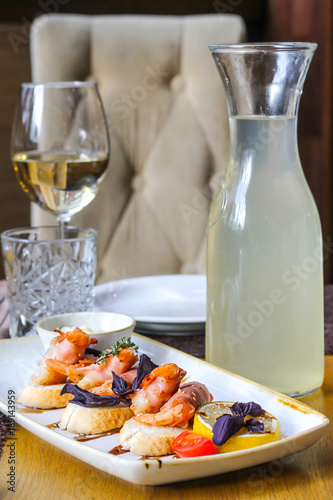 Baked shrimps in bacon on bruschettes with a glass of white wine and morsel - restaurant serve