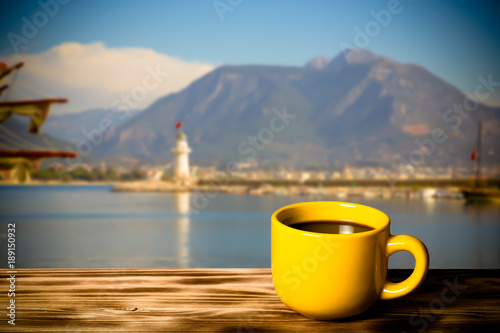 Yellow cup with tea on wooden table opposite a defocused  background. Collage. Selective focus. Toned photo
