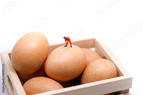 Miniature people : man working on eggs, idea or Easter day concept.