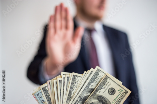 Bribe and corruption, offered cash to a businessman in a suit, does not want to take them, hold upright hands