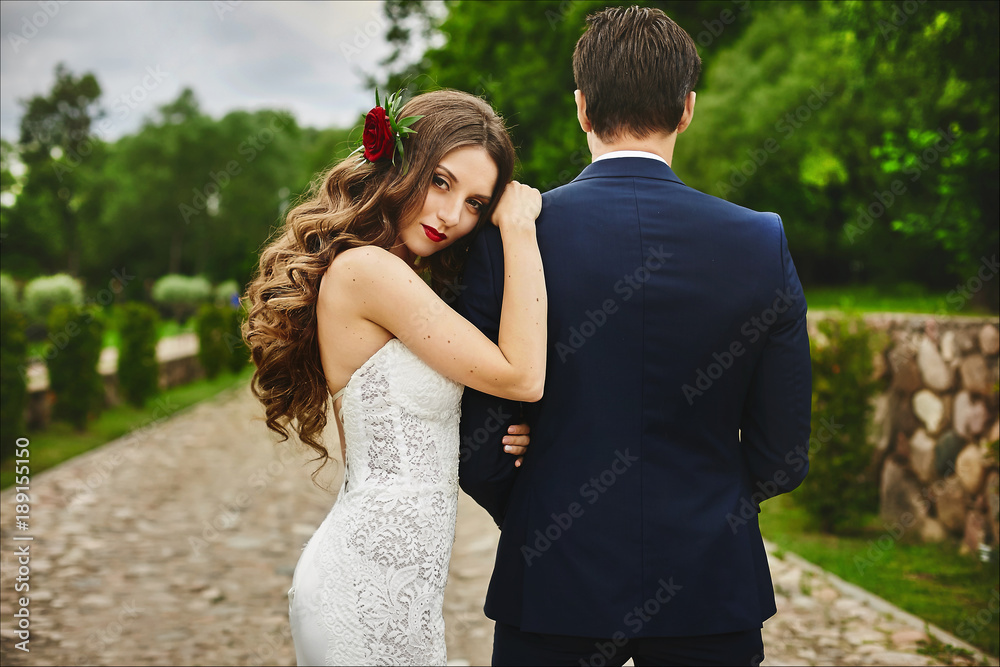 Cute brown-haired woman with cherry lips and a flower in curly hair put her head on the man's shoulder