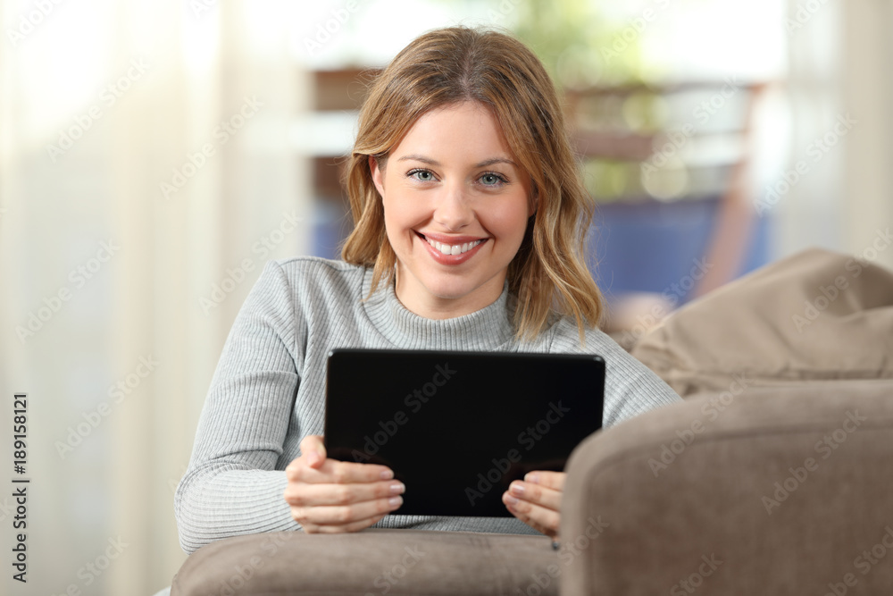 Happy girl holding a tablet and looking at camera