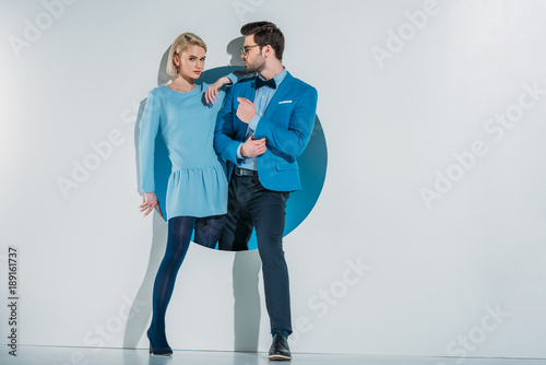 beautiful stylish young couple in blue clothes posing together in hole on grey