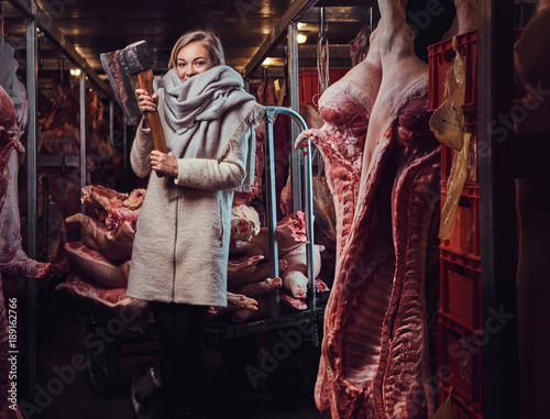 Blond female in a warm jacket in a meat freezer storage.