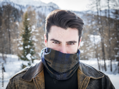 Portrait of adult handsome man covering face with scarf looking provocatively at camera.  photo