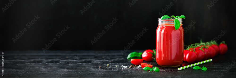 Organic fresh tomato juice in a glass jar, basil, cherry, salt, pepper and straw on dark black background. Clean eating and diet concept. Copy space Organic fresh tomato juice in a glass jar, basil, cherry, salt, pepper and straw on dark black background. Clean eating and diet concept. Copy space