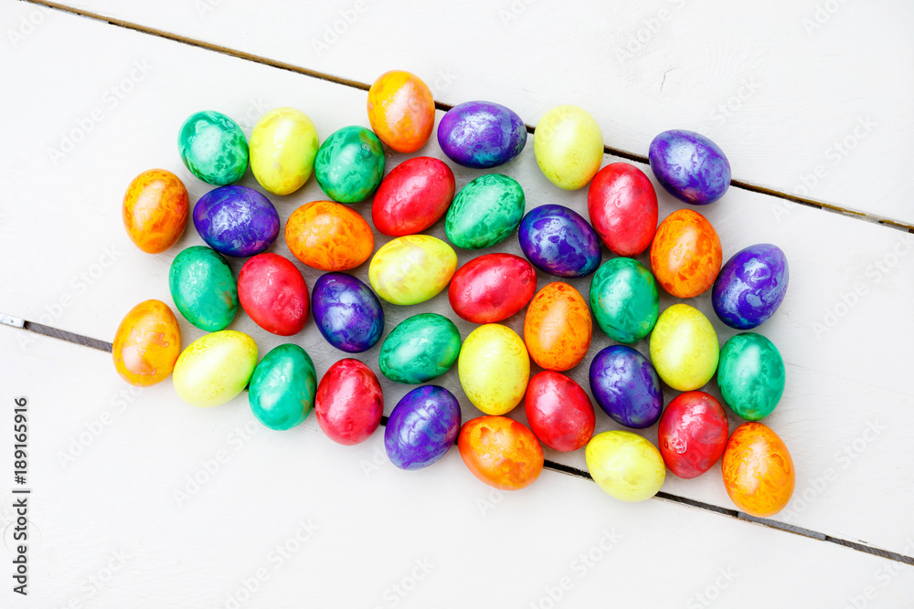 Easter eggs on wooden background. Colorful eggs in different colors - red, yellow, orange, purple and green.
