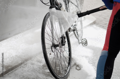 Man washing the bike with a strong jet of water. Washing the bike after the trip.