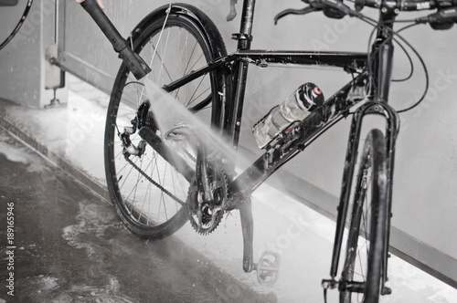 Man washing the bike with a strong jet of water. Washing the bike after the trip.