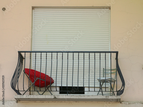 Bright red chair on a closed up apartment balcony, rural France