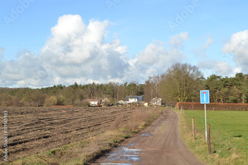 donkere wolken boven een boerderijtje aan een zandweg met verkeersbord in de Kruisbergse bossen photo
