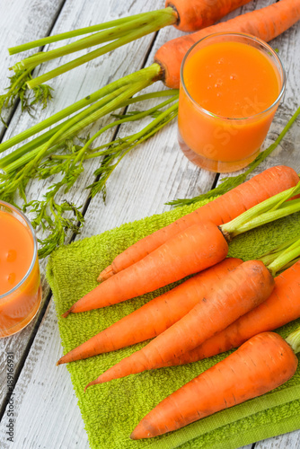 Two glasses of fresh carrot juice and bright orange carrots